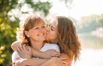 young woman cuddling and kissing her mother on the cheek