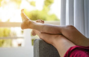 A person resting on a sofa with elevated legs.