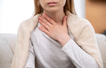 Close up view of female hand on neck, suffering from sore throat. Cropped view of sick woman feel discomfort in chest, painful, difficult to swallow. Concept of tonsillitis, angina, pectoris